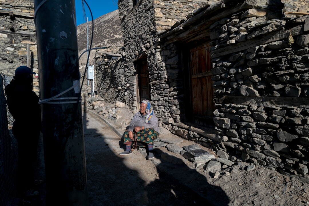 Photographer crouching to photograph an elderly woman in a village